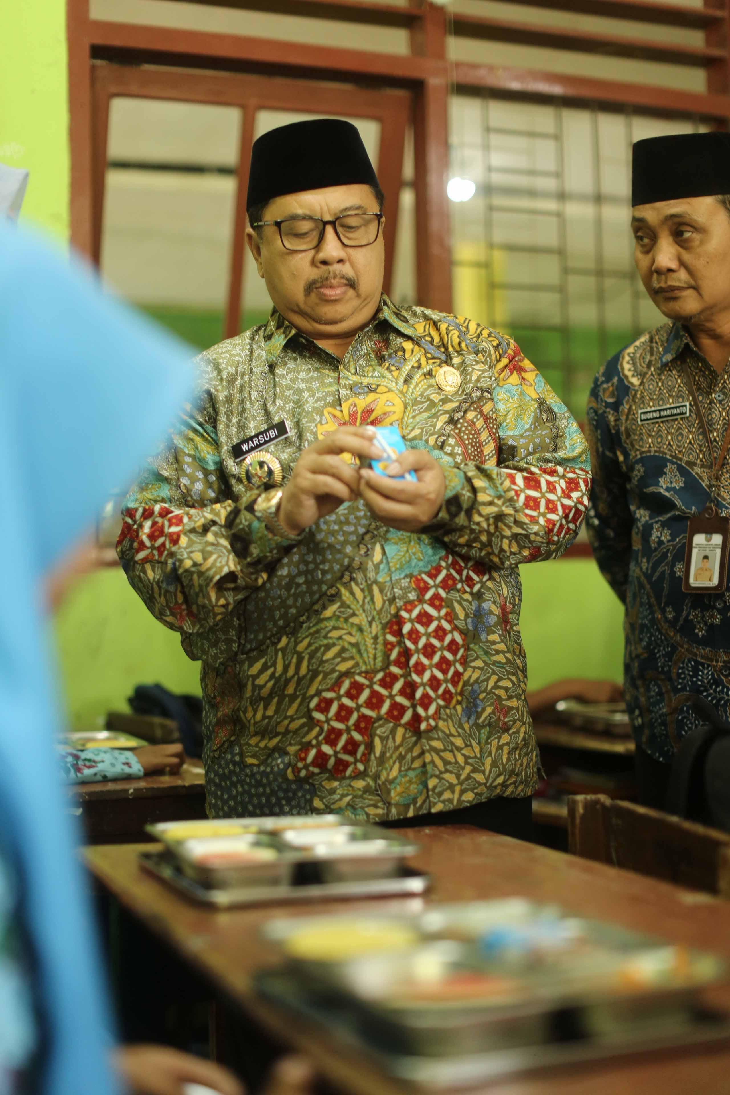 Warsubi menchek tanggal kedaluarsa susu kemasan untuk memastikan layak di konsumsi oleh siswa penerima program MBG. (Foto : Luhur Wijaya)
