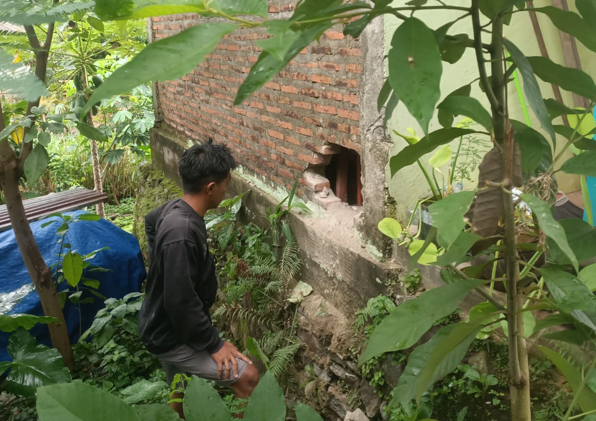 Sorang warga menunjukkan lokasi tembok yang dibobol pencuri di sebuah toko di Desa Sidolegi Kecamatan Wonosalam. (Foto:ist)